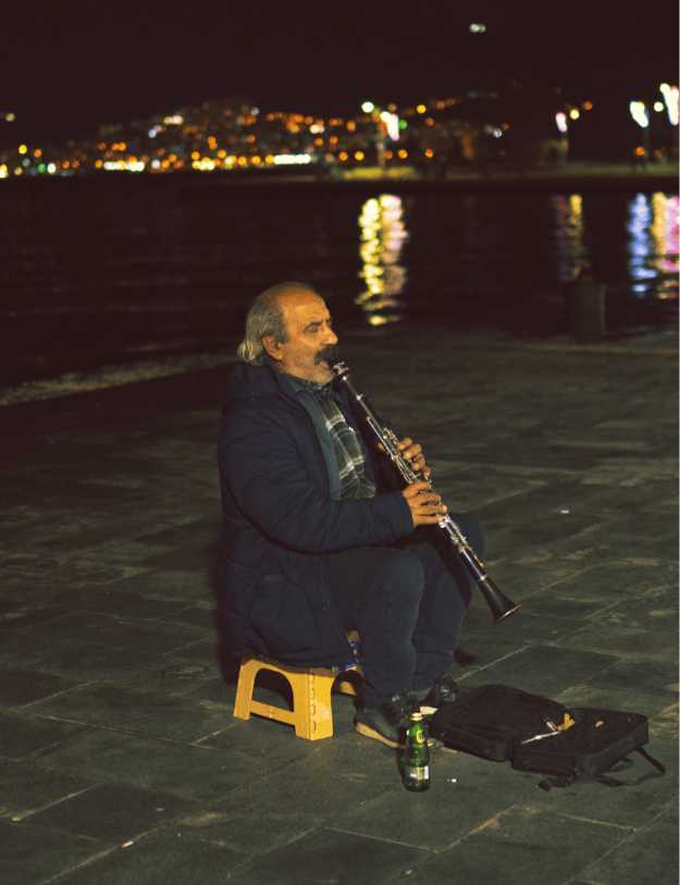 Older man sitting while playing the clarinet.