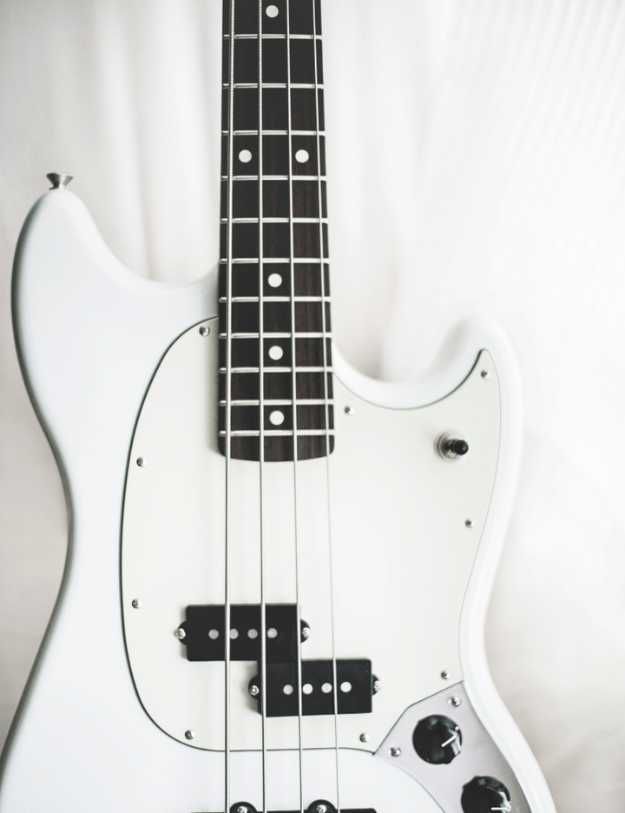 Close up of a white bass guitar.