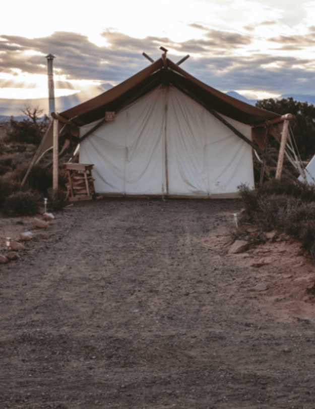 A canvas tent with decorations around it and the sun setting.