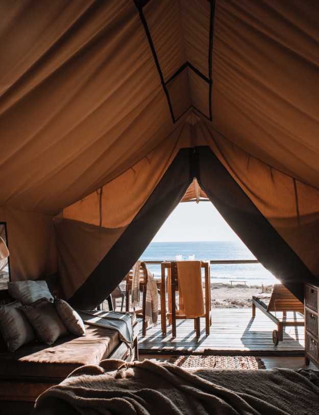 A view from the inside of a canvas tent looking on the beach.