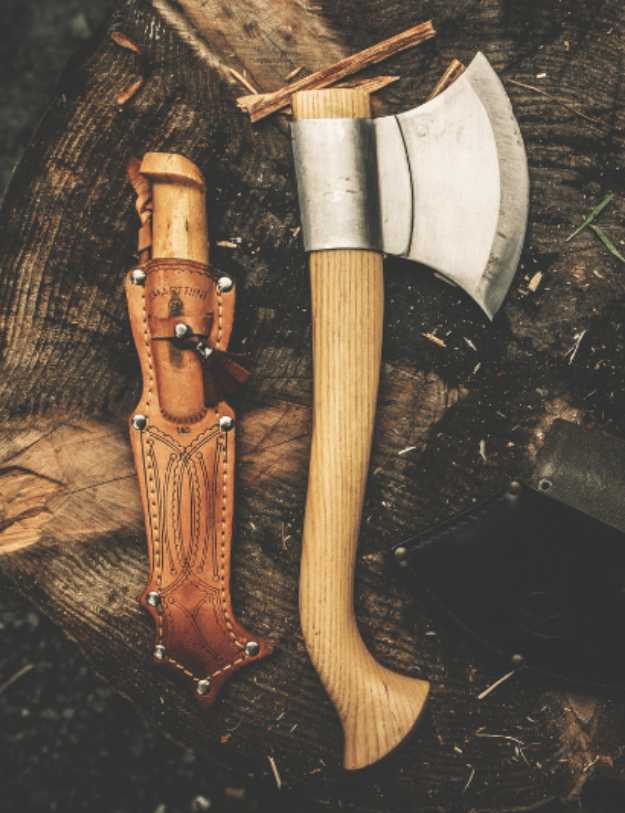 A knife and hatchet sitting next to each other on a stump.