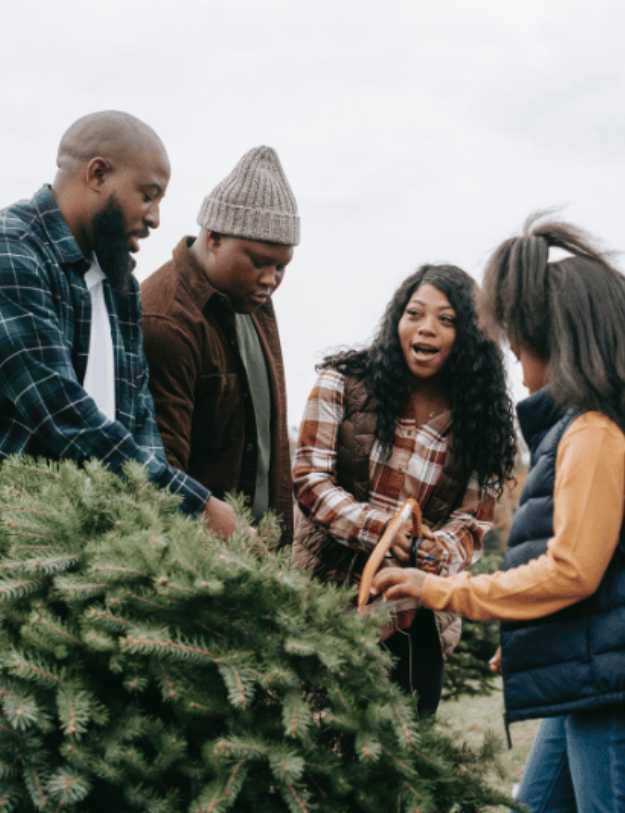 A colored family cutting a Christmas tree.