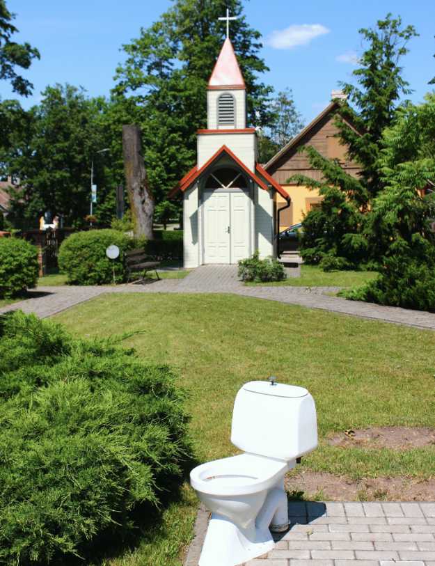 A toilet with a church in the background.