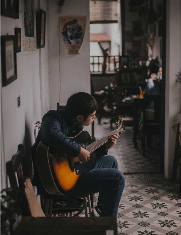 Man sitting in a hallway playing a guitar.