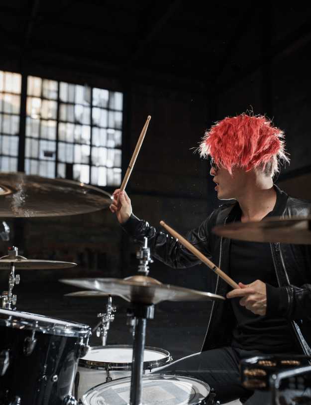 A person with red hair playing a drum set.