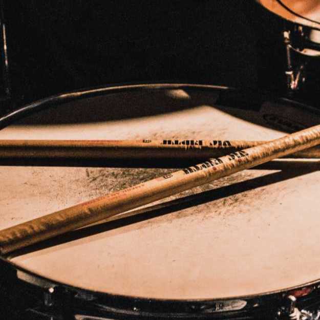 Used up drums sticks on a beaten up snare drum.