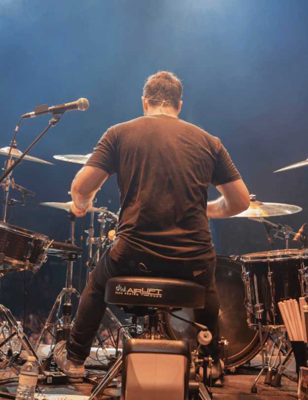 Behind view of a man playing the drums on stage.