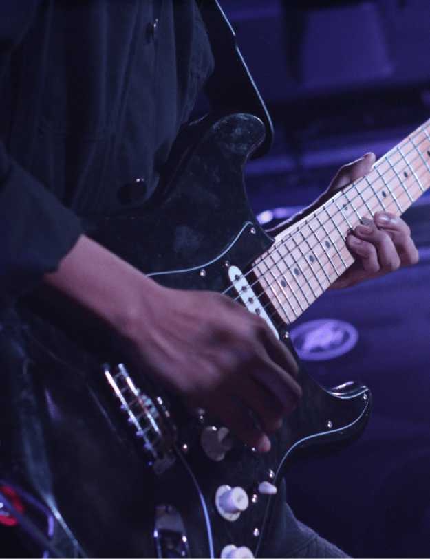 Man playing the guitar in a purple light.