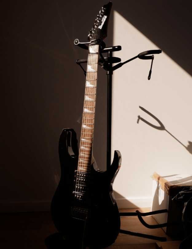 A black Ibanez guitar on a guitar stand.