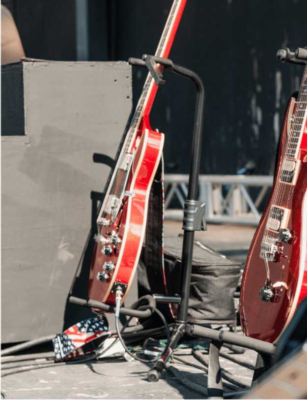 Two guitars on their stands on a stage.