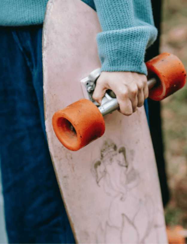 Person holding a longboard by its axis.