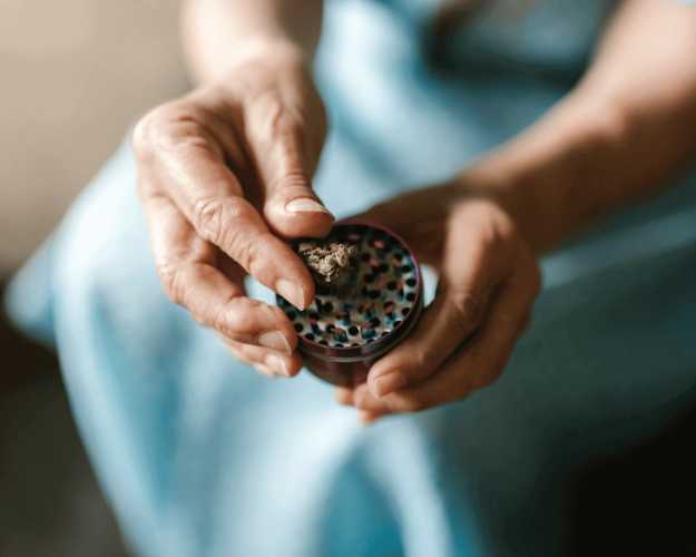 Older woman putting weed in a grinder
