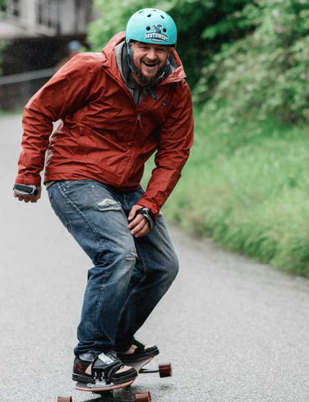 A happy man riding a board down a street