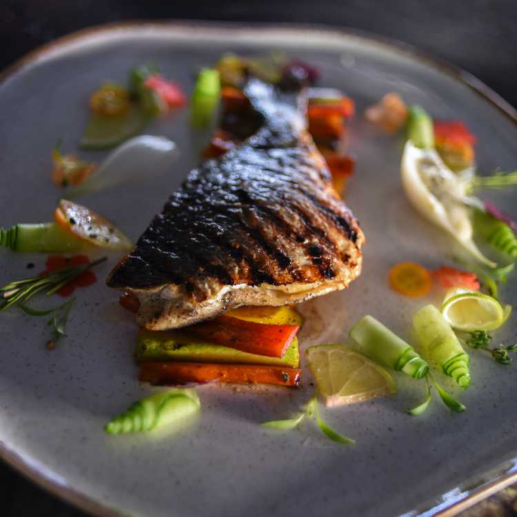Grilled tilapia on a plate with lime, peppers and other garnishes!