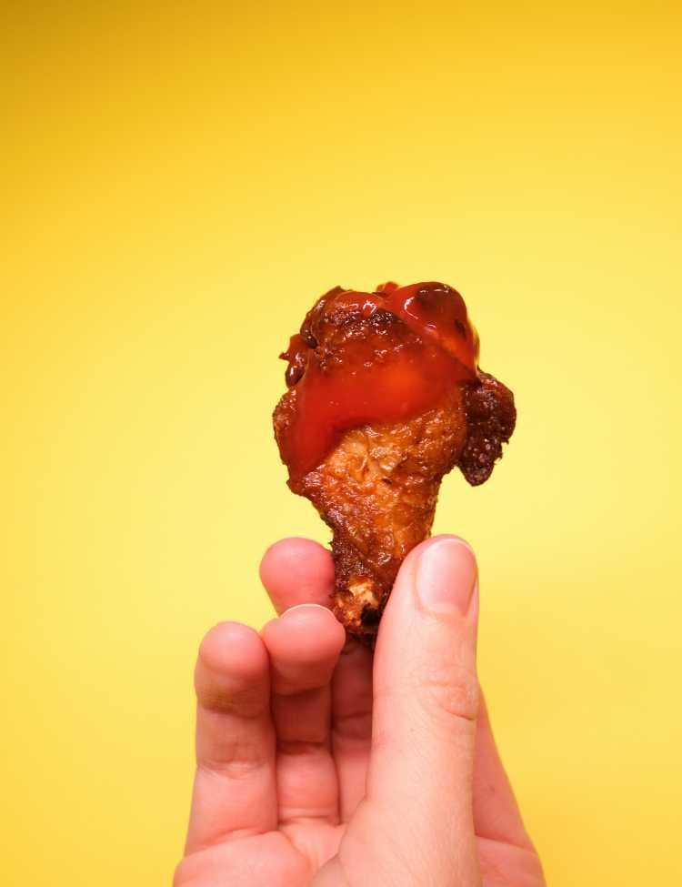 Person holding a chicken drumstick with sauce!