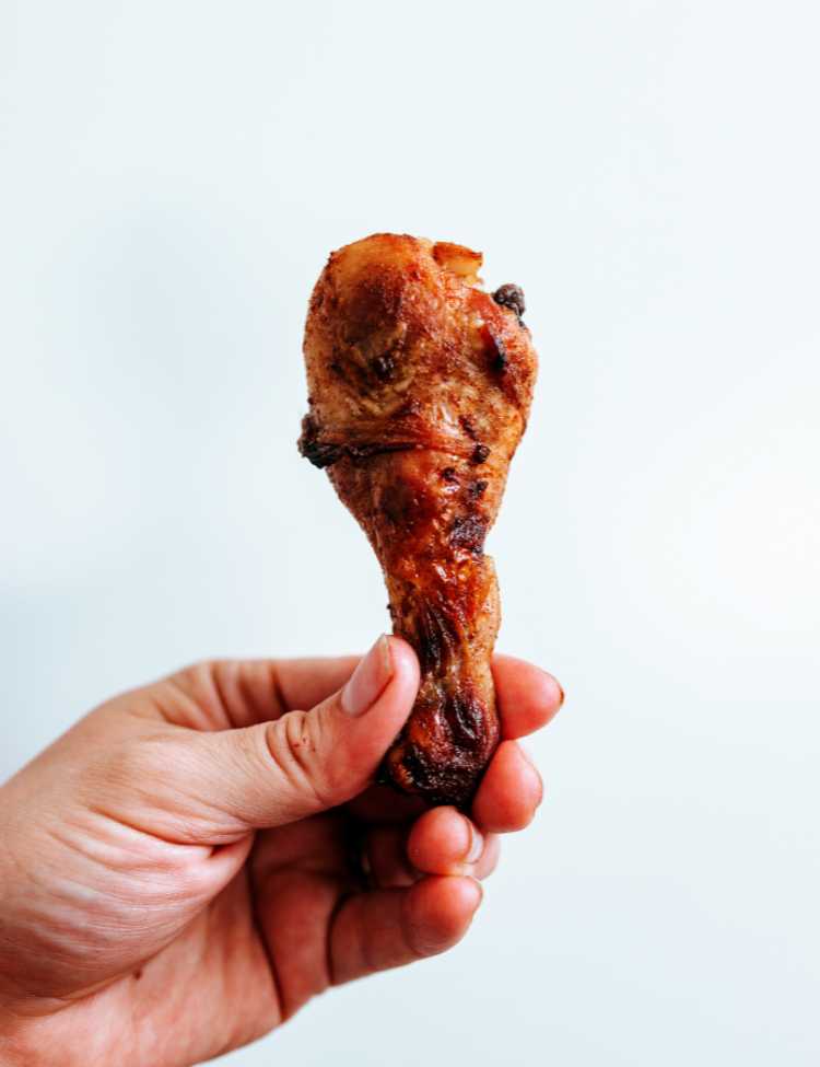 Person holding up a perfectly grilled drumstick. Perfect char and seasoning!