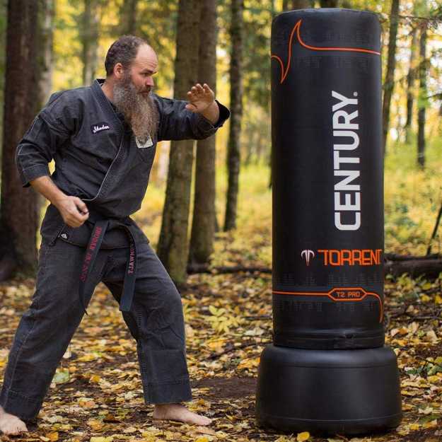 Man in woods punching a free standing bag