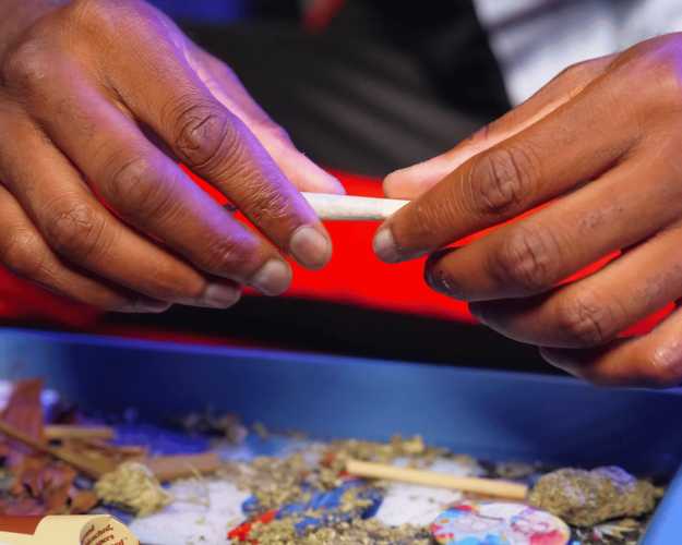 A colored man holding a joint with both hands