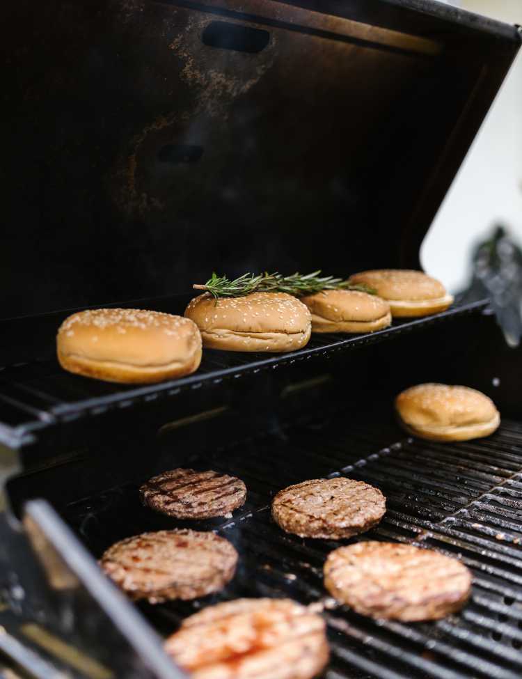 Burgers being grilled while the buns are on the upper warming rack.