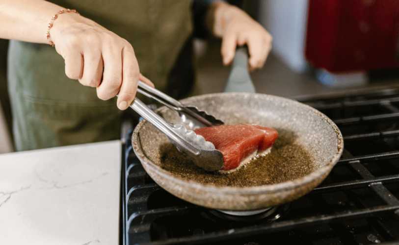 Meat being seared onto a pan