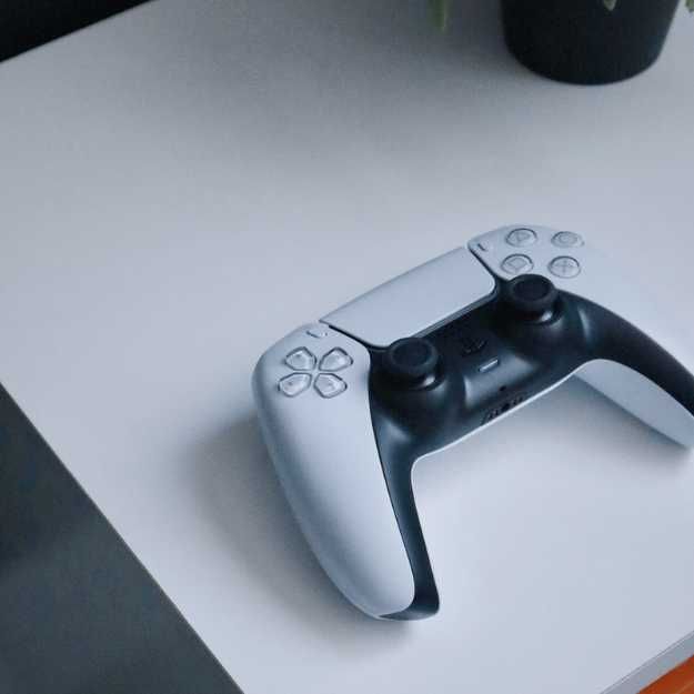 A PS5 controller on a white surface.