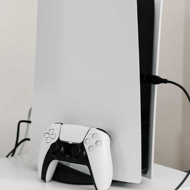 A PS5 controller leaning against a PS5.
