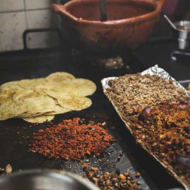 Seasonings on a countertop with tortillas and bowls.
