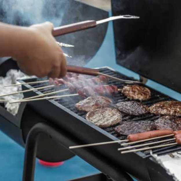 Someone using tongs to grill various meats.