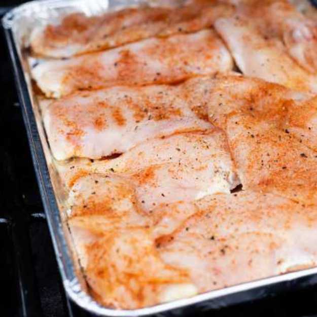 Raw chicken in a tray going into the oven.