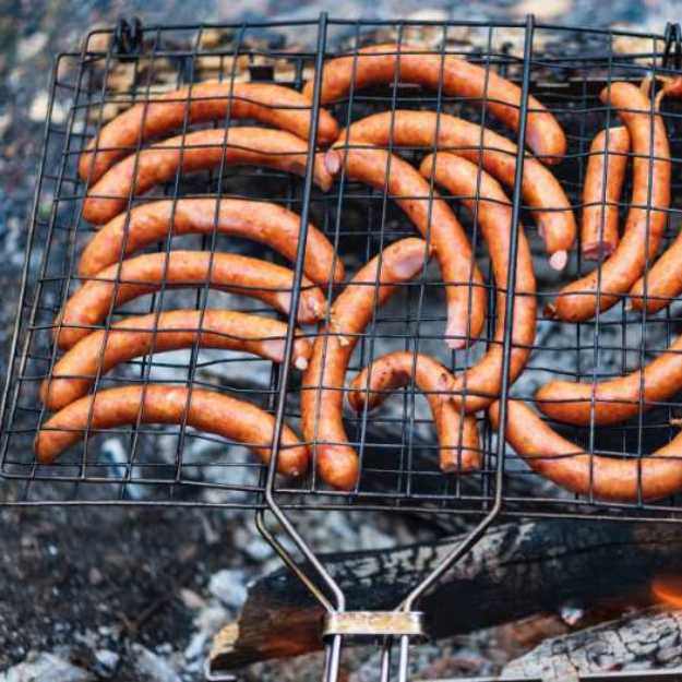 Wieners in an closed wire grill.