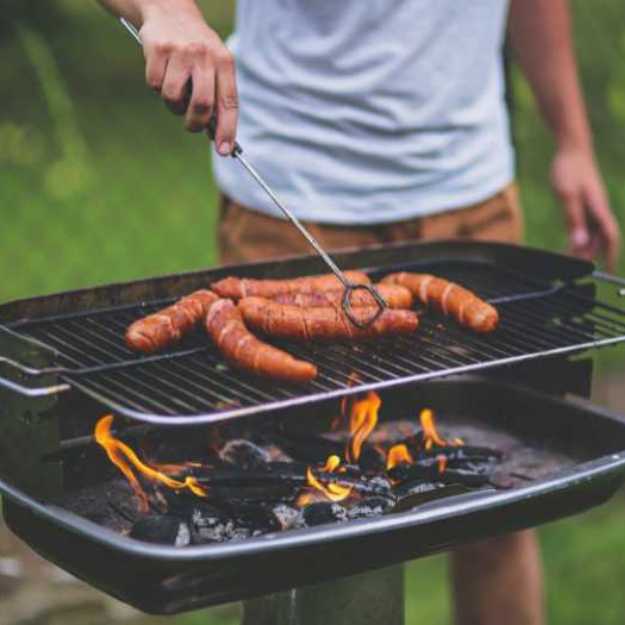 Someone grilling wieners in an outside grill.