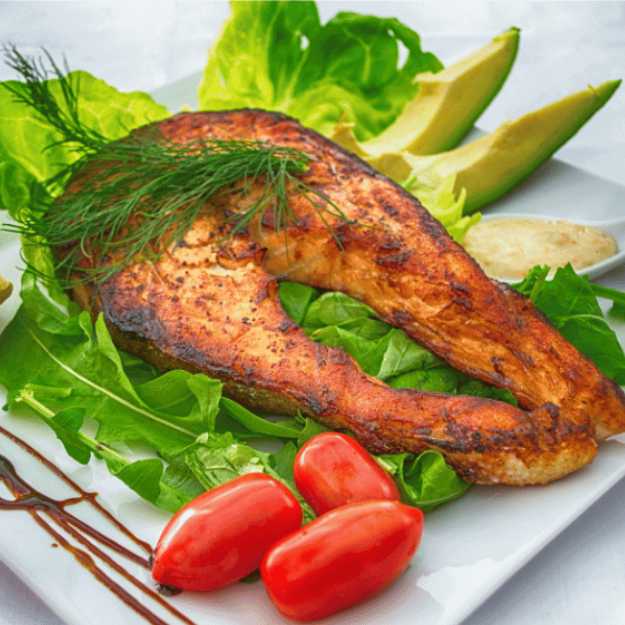A Grilled fish on a bed of lettuce and tomatoes.