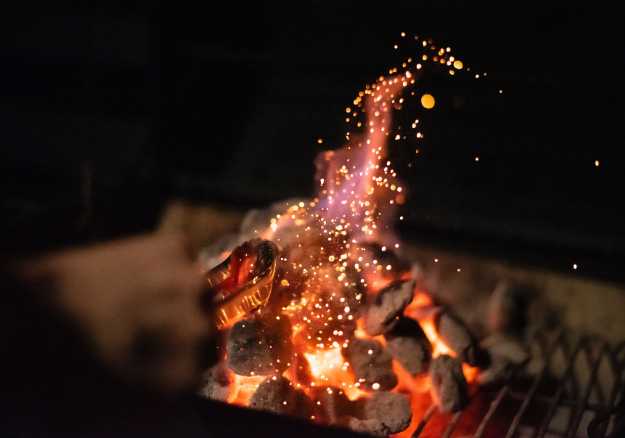 A person cooking over open charcoal grill