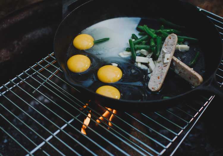 Green beans being grilled in a pan along with other foods like eggs and sausage!