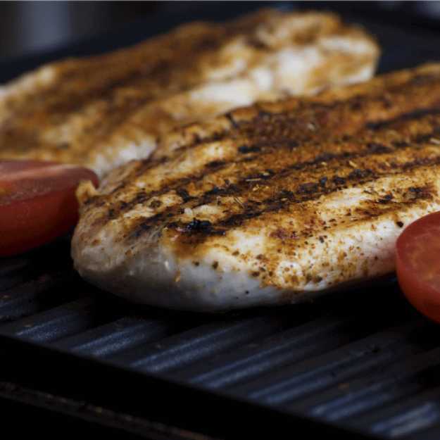 Close up grilled fish with tomatoes on a grill.