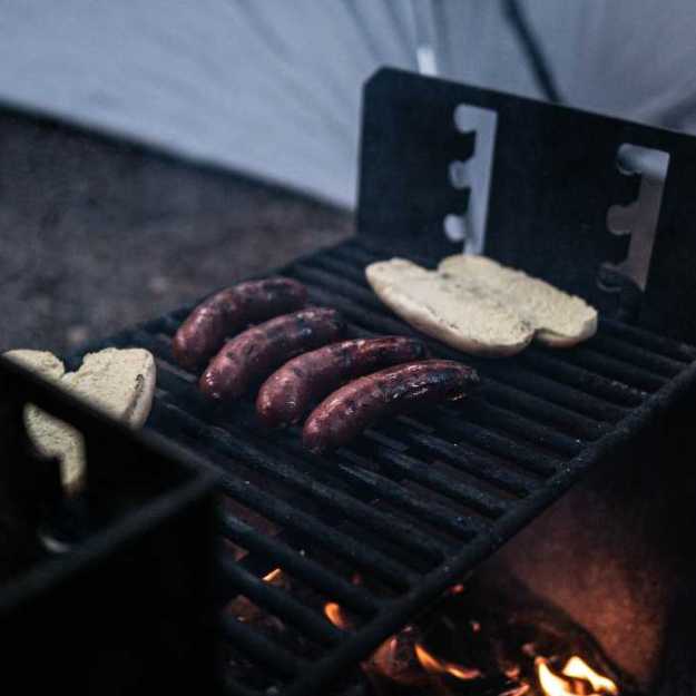 Hot dogs with their buns on a grill.