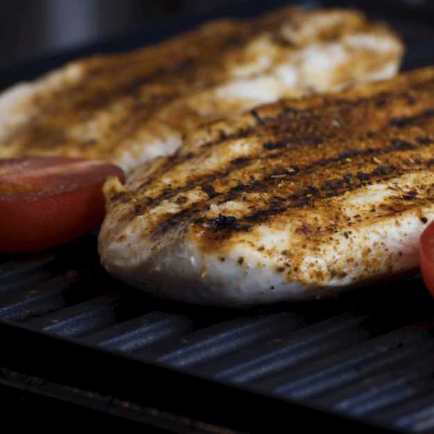 Grilled chicken with tomatoes on a grill.
