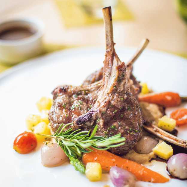 Lamb chops displayed on a plate with veggies.