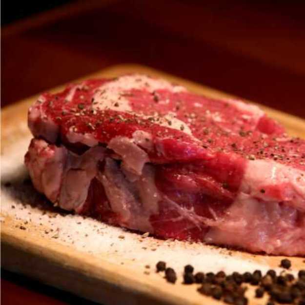 A Raw steak on a cutting board with seasonings.