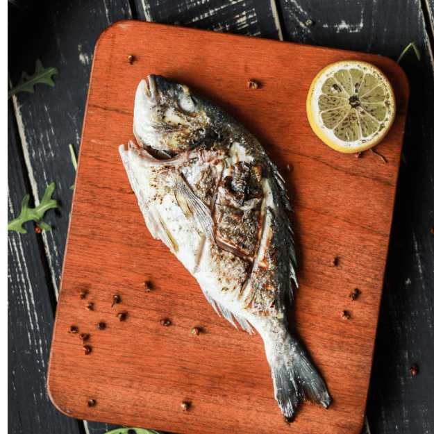 A Whole grilled fish on a cutting board.