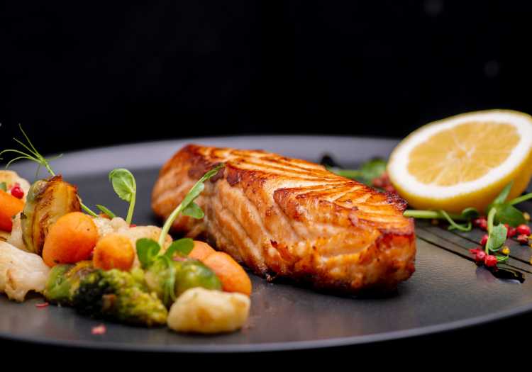 Beautifully cooked salmon on a plate with sides and garnishes