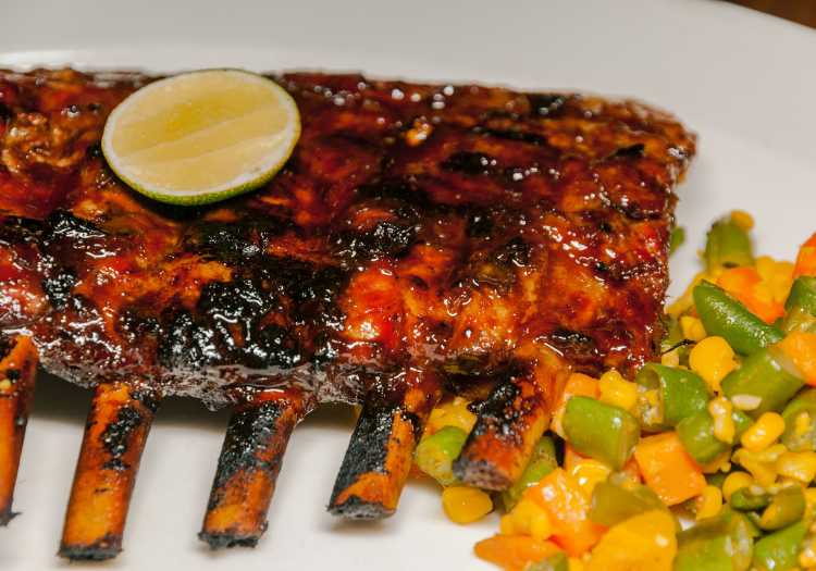 Pellet smoked ribs, garnished and plated with side dishes.