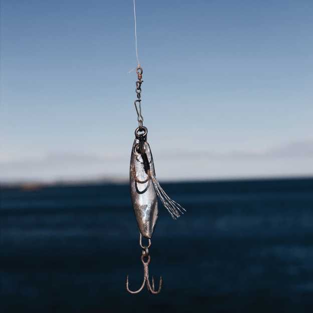 A Fishing lure and hook with the ocean in the background.