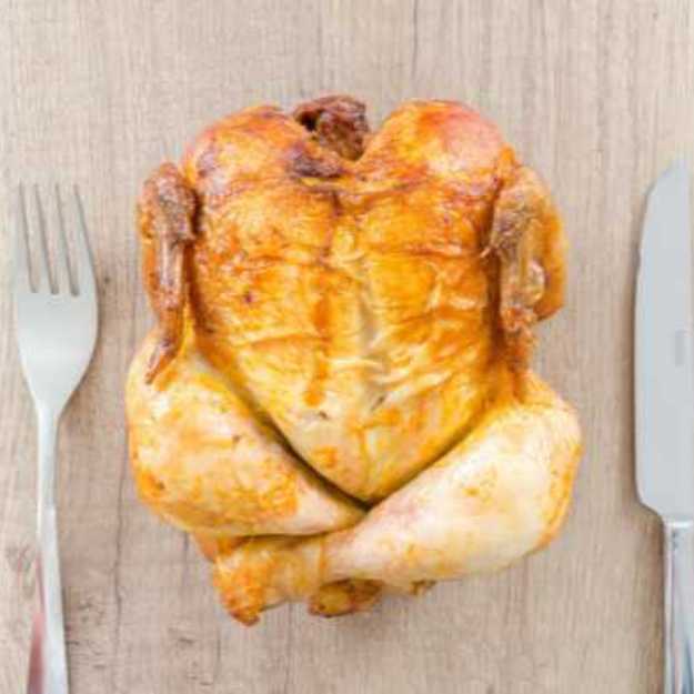 A Whole chicken with a knife and fork on each side.