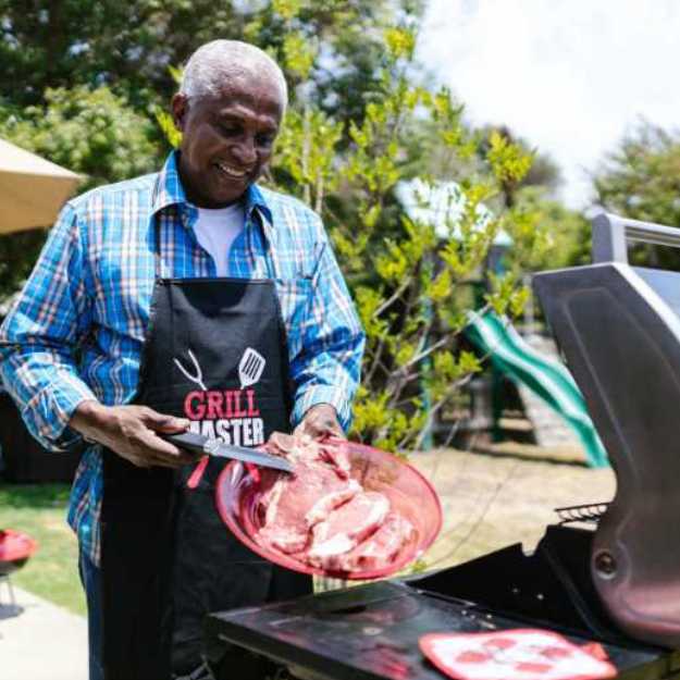 An Older colored man holding a plate with steaks.