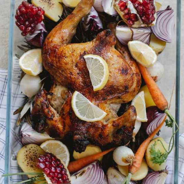 A Whole chicken with various of fruits and veggies soaking into it.
