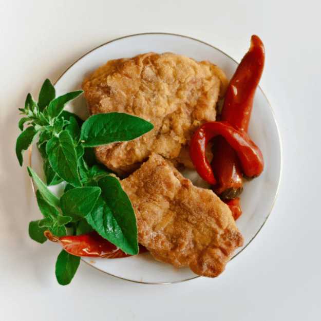 Fried fish with peppers and herbs on a plate.