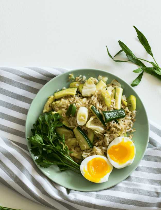 A plated filled with a healthy breakfast of greens, grains, and eggs.