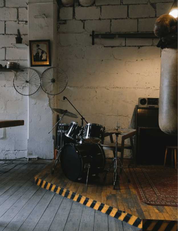 Showcase of someones basement with a drum kit in the middle.
