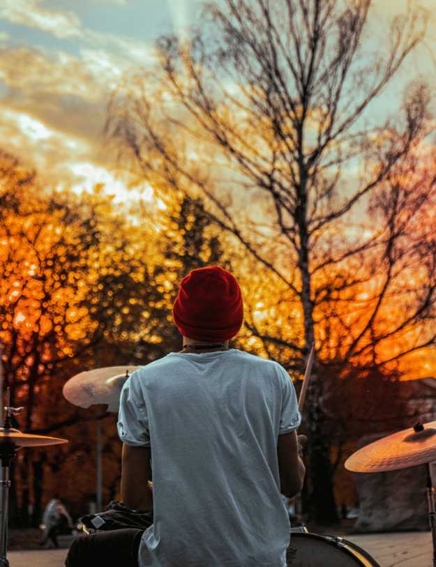 Someone playing the drums during a sunset.